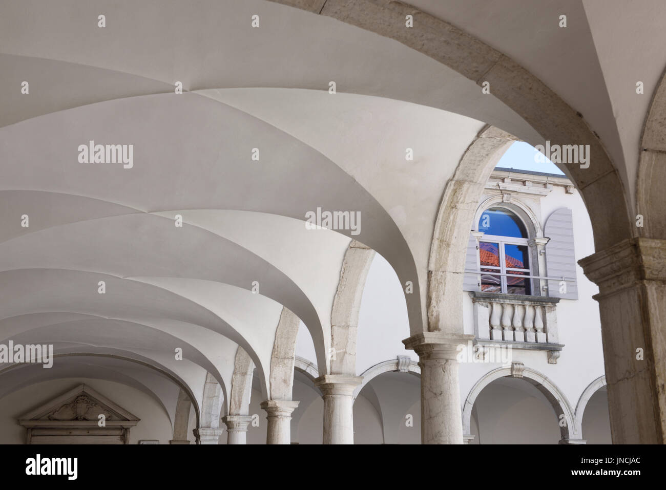 Half arched portal of the Minorite Monastery cloister attached to the Church of St Francis of Assisi in Piran Slovenia with window reflection color Stock Photo