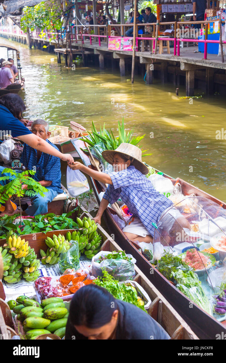 Thai woman in a boat receiving payment from customer at Khlong Lat Mayom Floating Market, Bangkok Thailand Stock Photo