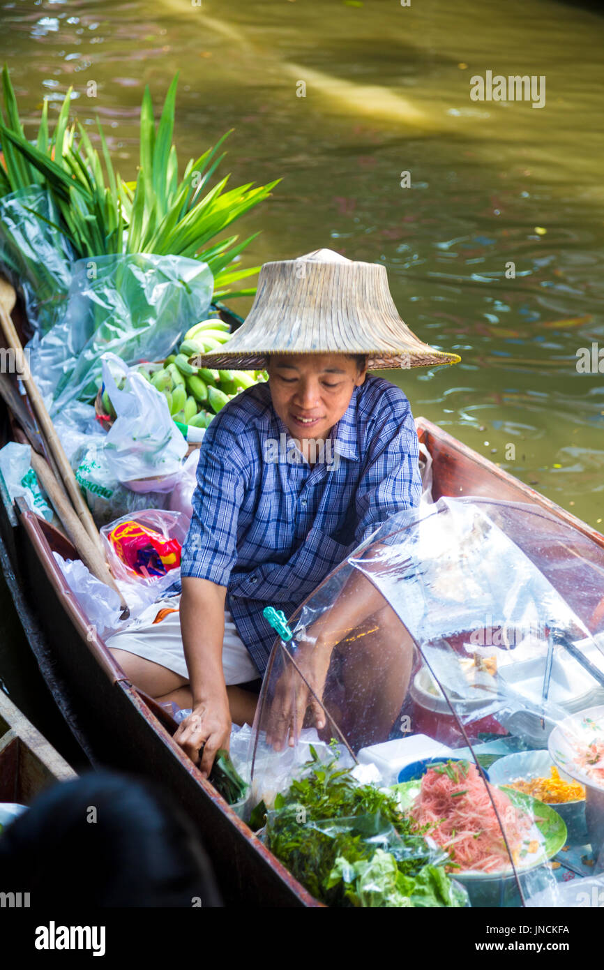 Thai woman in a hat sitting in a boat selling fruit and vegetbles at Khlong Lat Mayom Floating Market, Bangkok Thailand Stock Photo