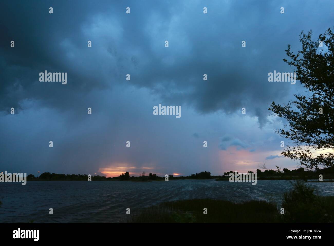 Huge Bank of Rain Clouds Approaching Over Lake at Sunset Stock Photo