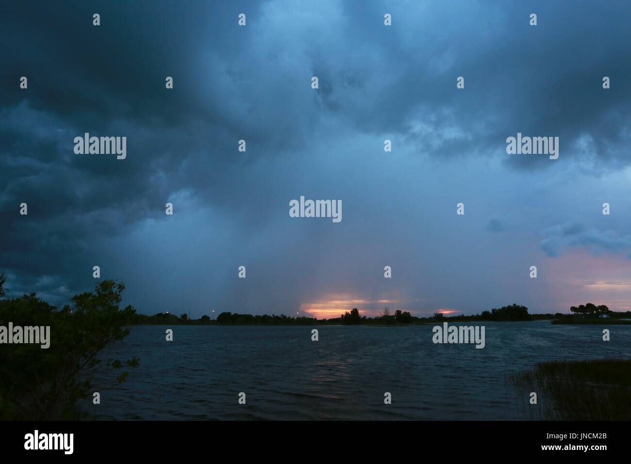 Huge Bank of Rain Clouds Approaching Over Lake at Sunset Stock Photo