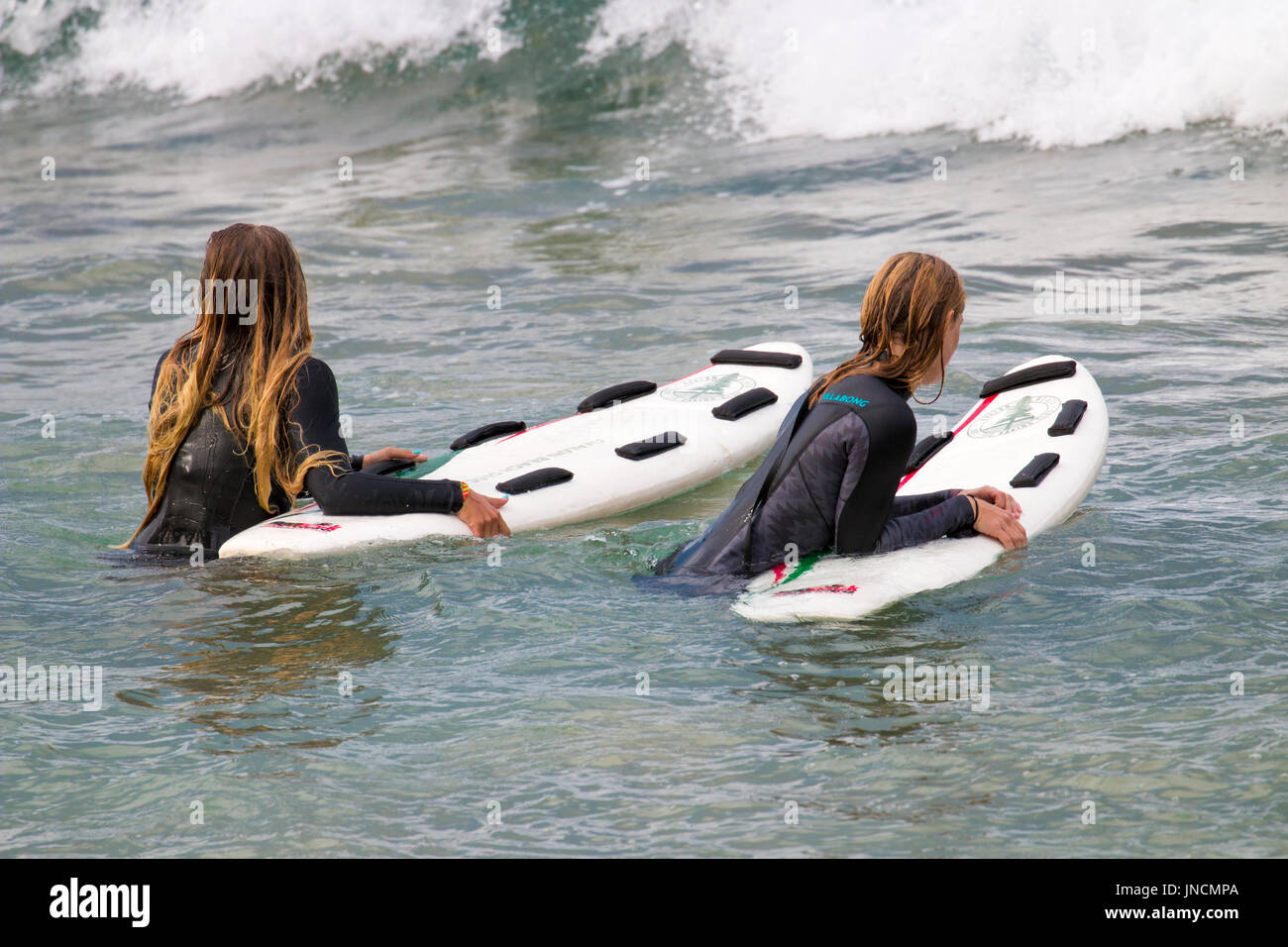 Two Australian girls in the ocean off a Sydney beach wearing wetsuits