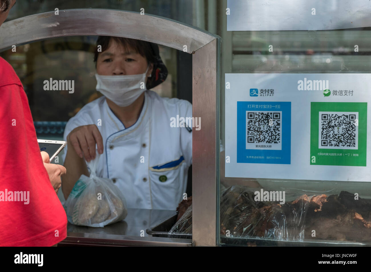 People buy snacks at an ordinary food store with QR code and mobile phone, using Alipay, WeChat Pay in Beijing, China. 30-Jul-2017 Stock Photo