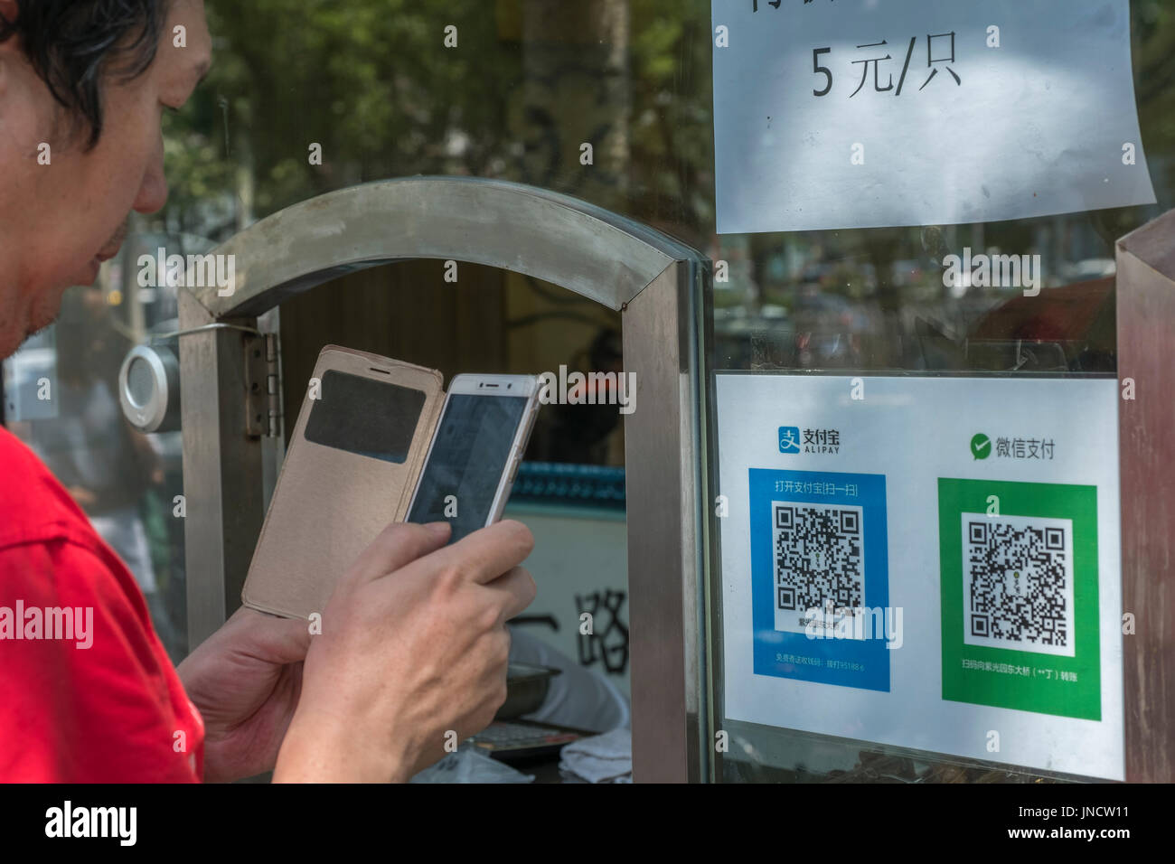 People buy snacks at an ordinary food store with QR code and mobile phone, using Alipay, WeChat Pay in Beijing, China. 30-Jul-2017 Stock Photo