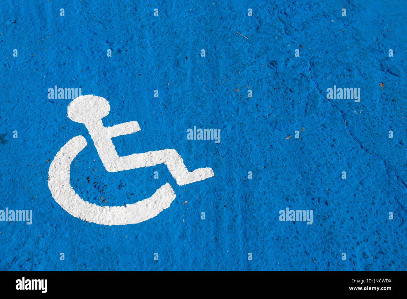 White disabled parking sign painted on blue background Stock Photo