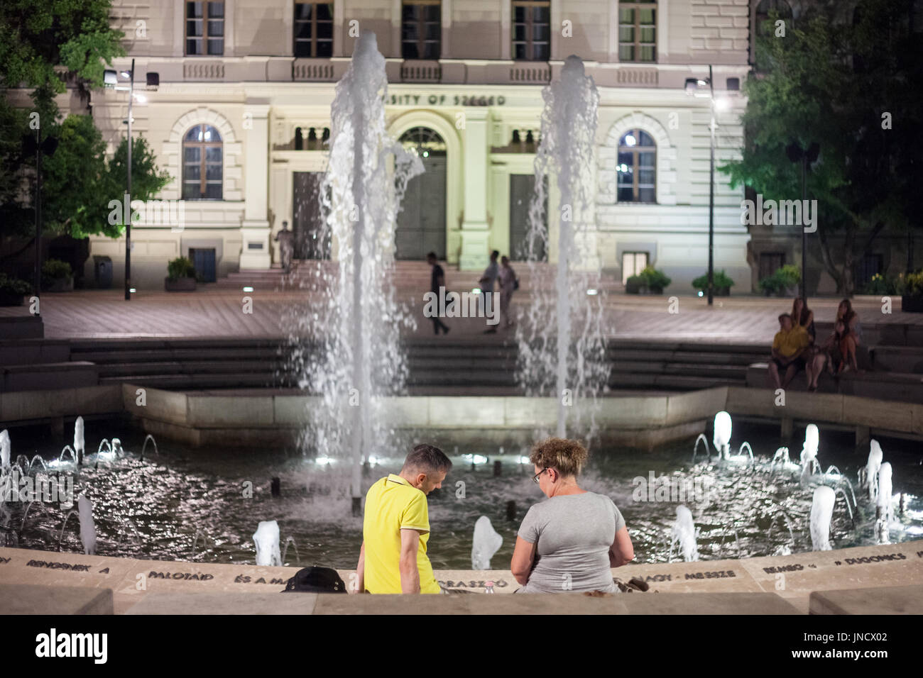 SZEGED, HUNGARY - JULY 20, 2017: Lovers in front of the Fountain on Dugonics Ter Square at night in summer. This square, and the university building o Stock Photo