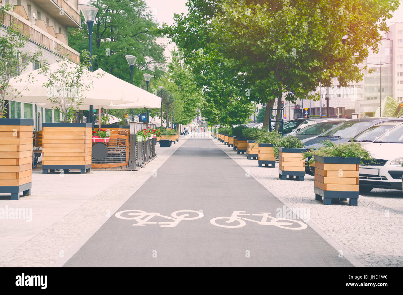 City street with long bicycle lane near outdoor cafe; Sunny effect Stock Photo