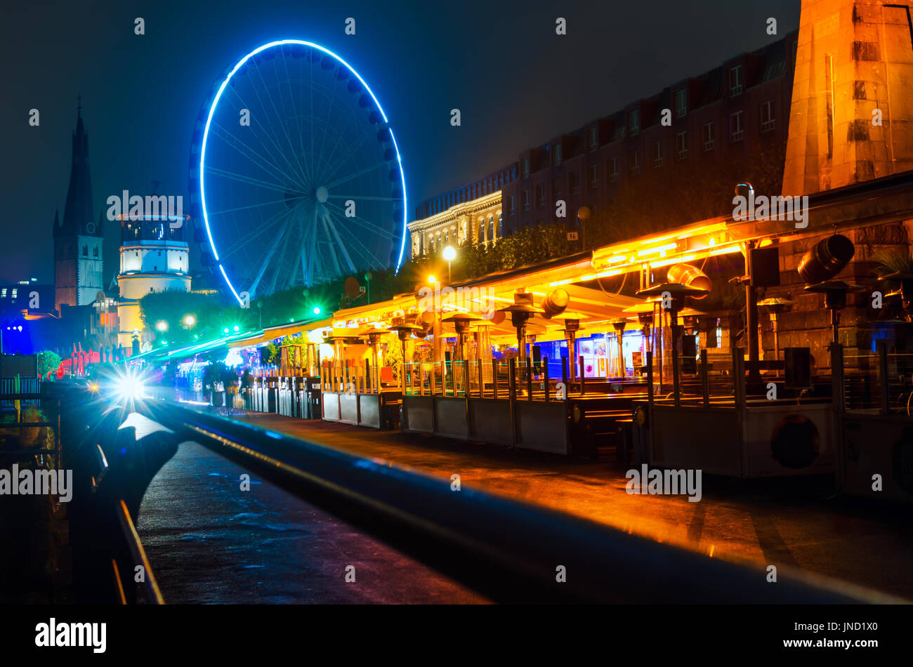 Restaurants, bars and pubs on Dusseldorf city street at night near embankment of Rhine river