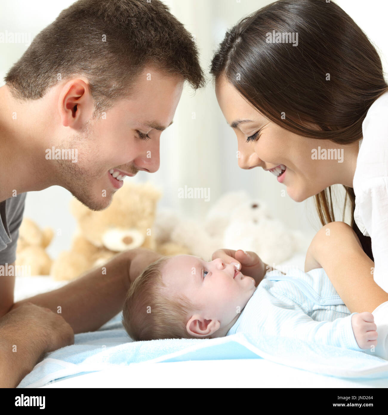 Proud parents watching their son on a bed at home Stock Photo