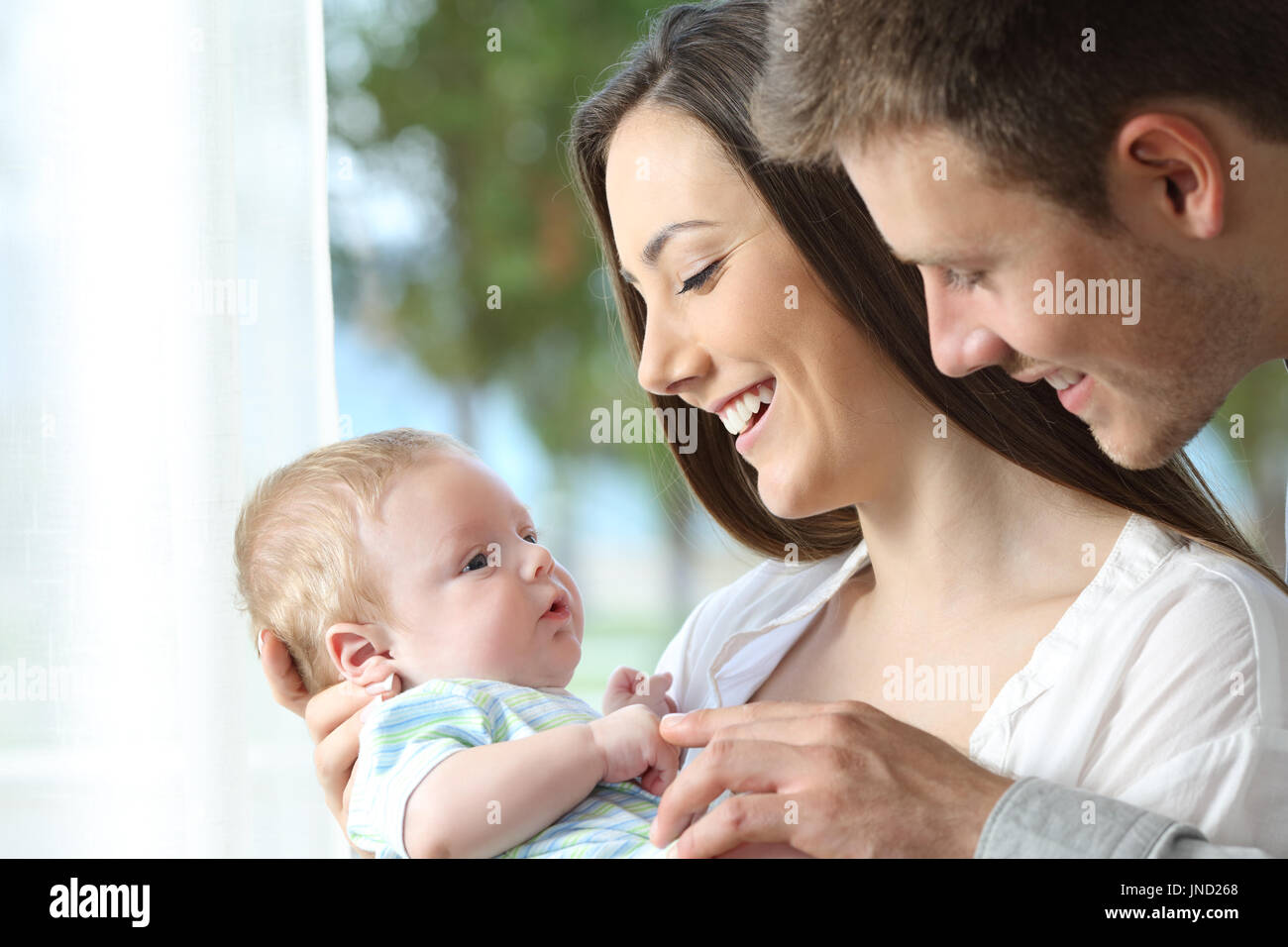 Proud parents holding and playing with their baby at home Stock Photo