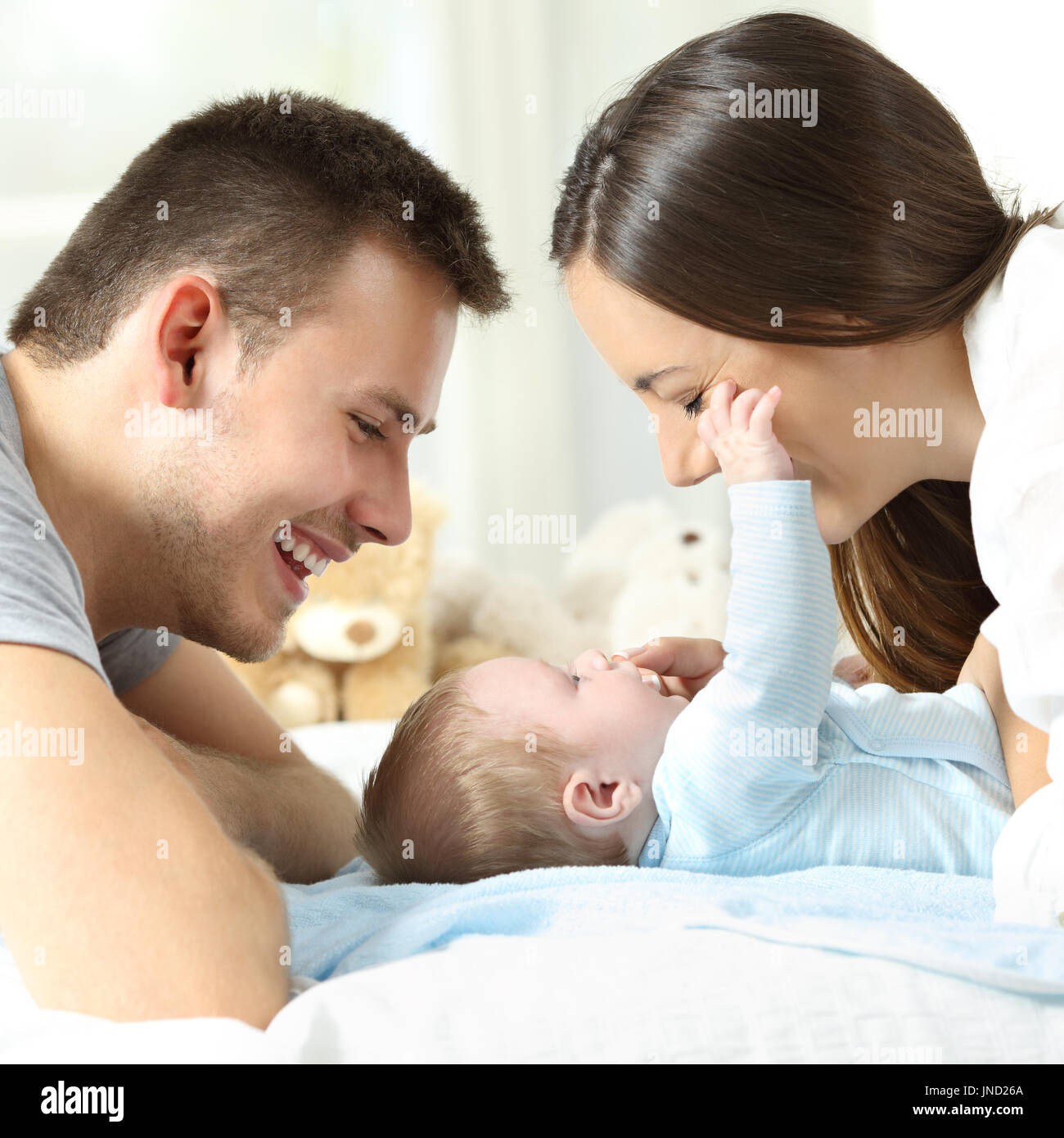 Side view close up of a baby playing with his parents on a bed Stock Photo