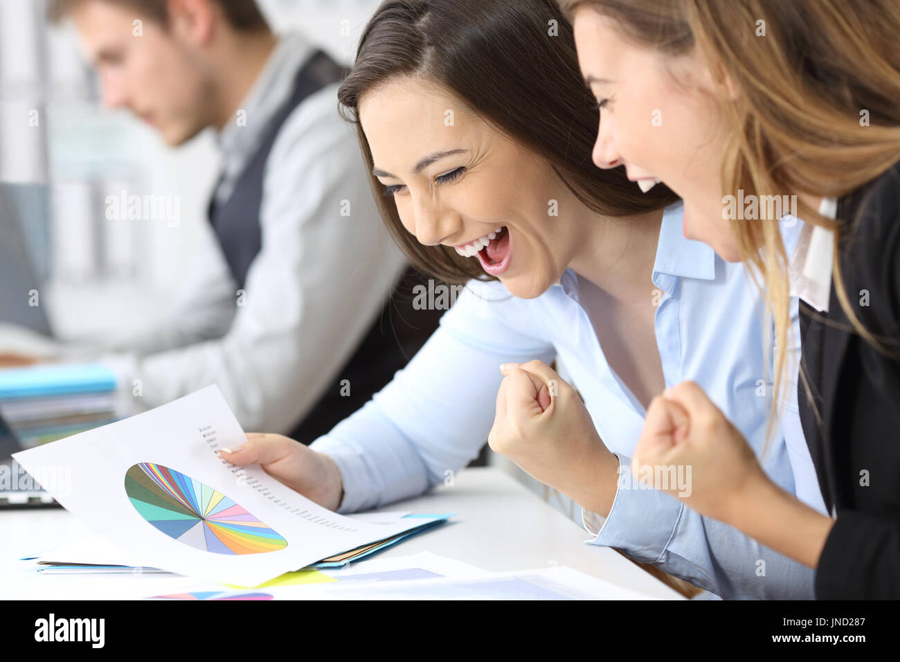 Two excited businesswomen celebrating success reading growth graphs at office Stock Photo