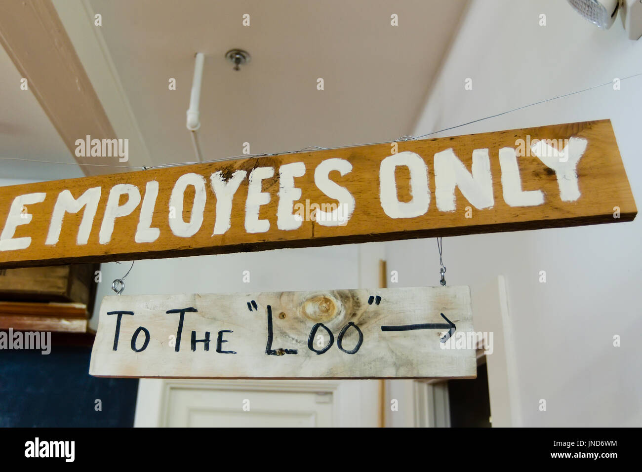 Wooden signs 'Employees Only' and 'To The Loo' hanging from ceiling Stock Photo