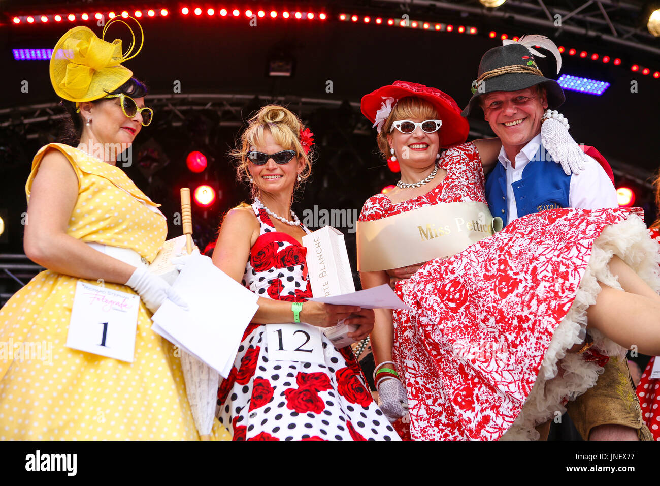 Wettenberg, Germany. 30th July, 2017. Miss Petticoat Contest at Golden Oldies Festival in Wettenberg, Germany. Miss Petticoat 2017 is Britta Ullmann (right), from Giessen, Hesse, Germany, in arms of juror Hansi Rieser. 3rd place: Viola Kornfeld (left, no 1, yellow dress), from Bad Hersfeld, Hesse, Germany. 2nd place: Anke Beger (second from left, no.12), from Freiberg, Saxony, Germany. The Golden Oldies Festival is an annual nostalgic festival (est. in 1989) with focus on 1950s to1970s, over 1000 exhibited classic cars and old-timers, over 50 live bands. Credit: Christian Lademann Stock Photo