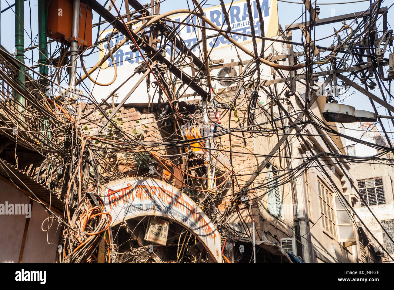 A tangle of utility wires and cables above the streets in Chandni Chowk, a wholesale market in Old Delhi, India. Stock Photo