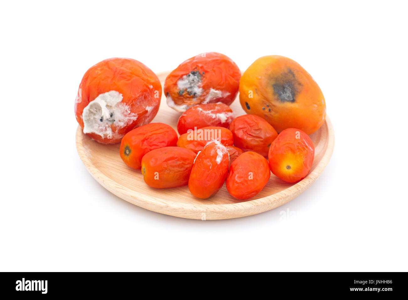 rotten tomato on wooden plate isolated on white background Stock Photo