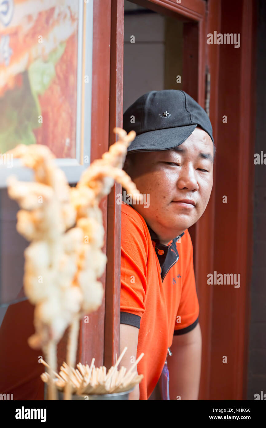 Chinese salesman preparing meat on traditional food market. Wangfujing