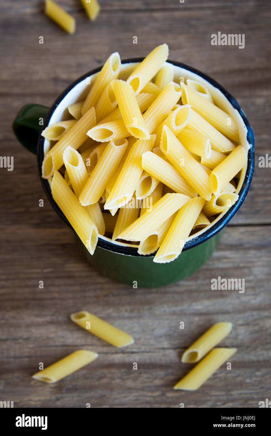 Uncooked raw italian penne pasta in metal mug healthy ingredient for