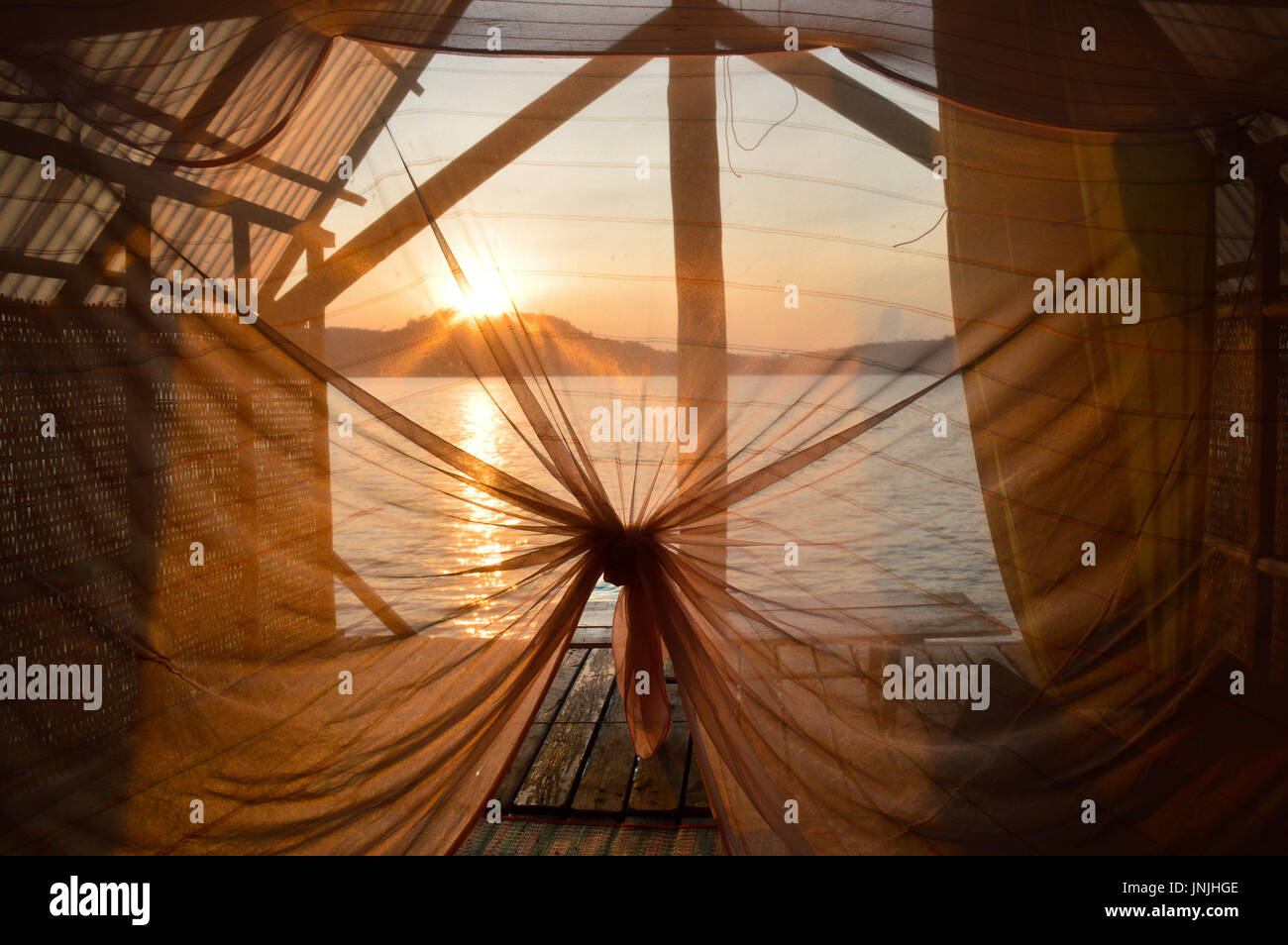 View Of The Sunset From The Inside Of A Beach Cottage With Canopy