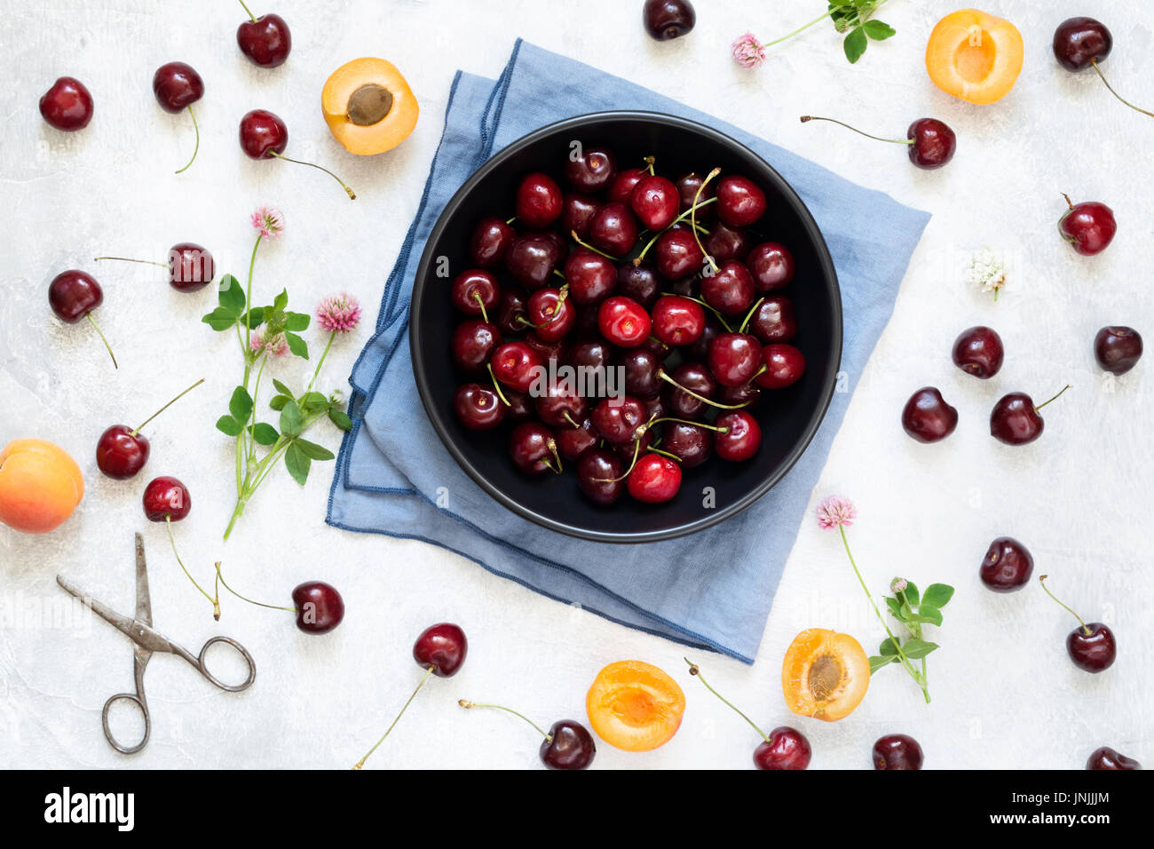 Berry flat lay with sweet cherries, apricots and clover leaf on white