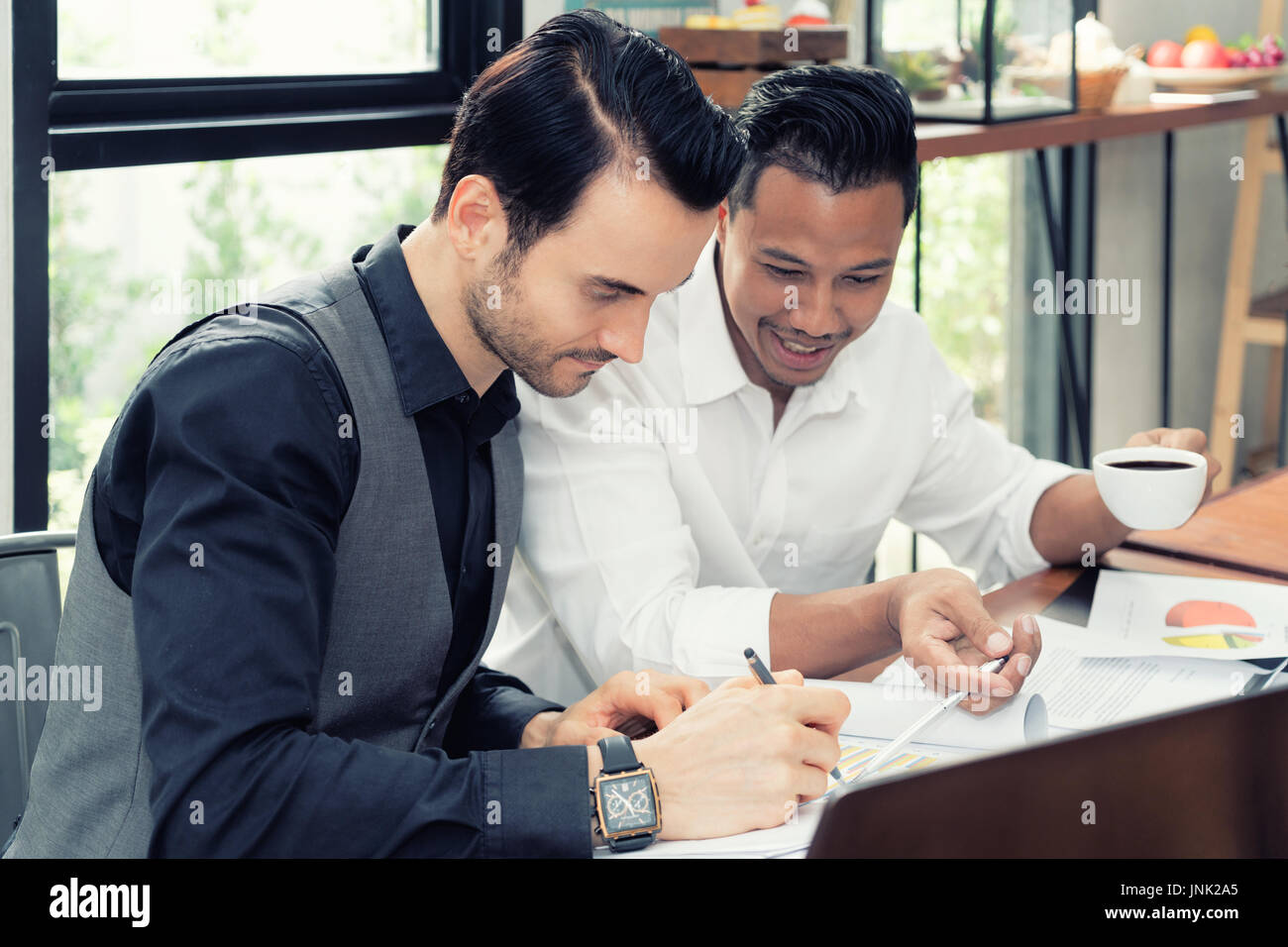 Two young Multiethnic businessman working on table In coffee shop. Stock Photo