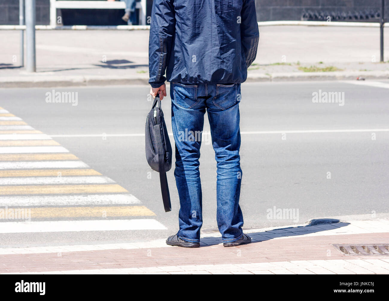 man waiting to cross the street on sunny summer day Stock Photo