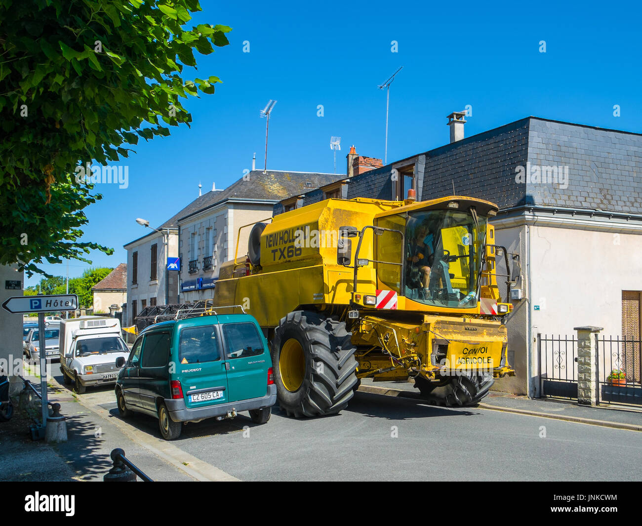 'New Holland TX66' combine harvester on narrow town street, Martizay, France. Stock Photo