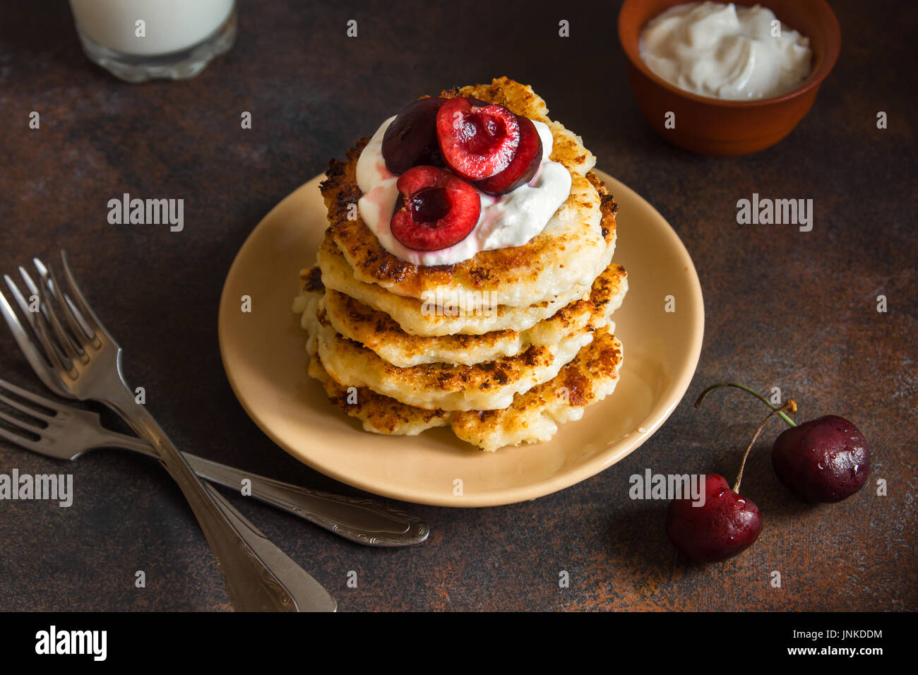 Rustic homemade curd pancakes with yogurt sauce and cherry for