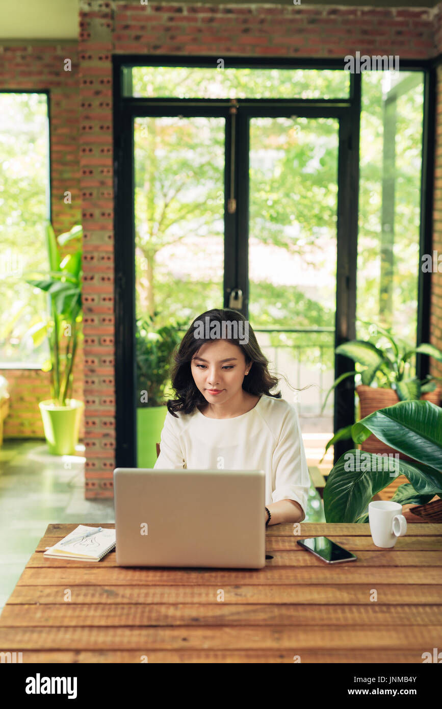 Beautiful young smiling woman working on laptop while sitting on bed at ...
