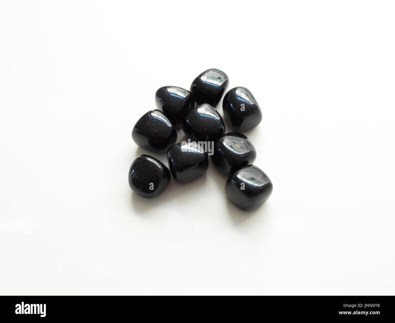 Tumbled Black Obsidian stones close up on table for crystal therapy treatments and reiki Stock Photo