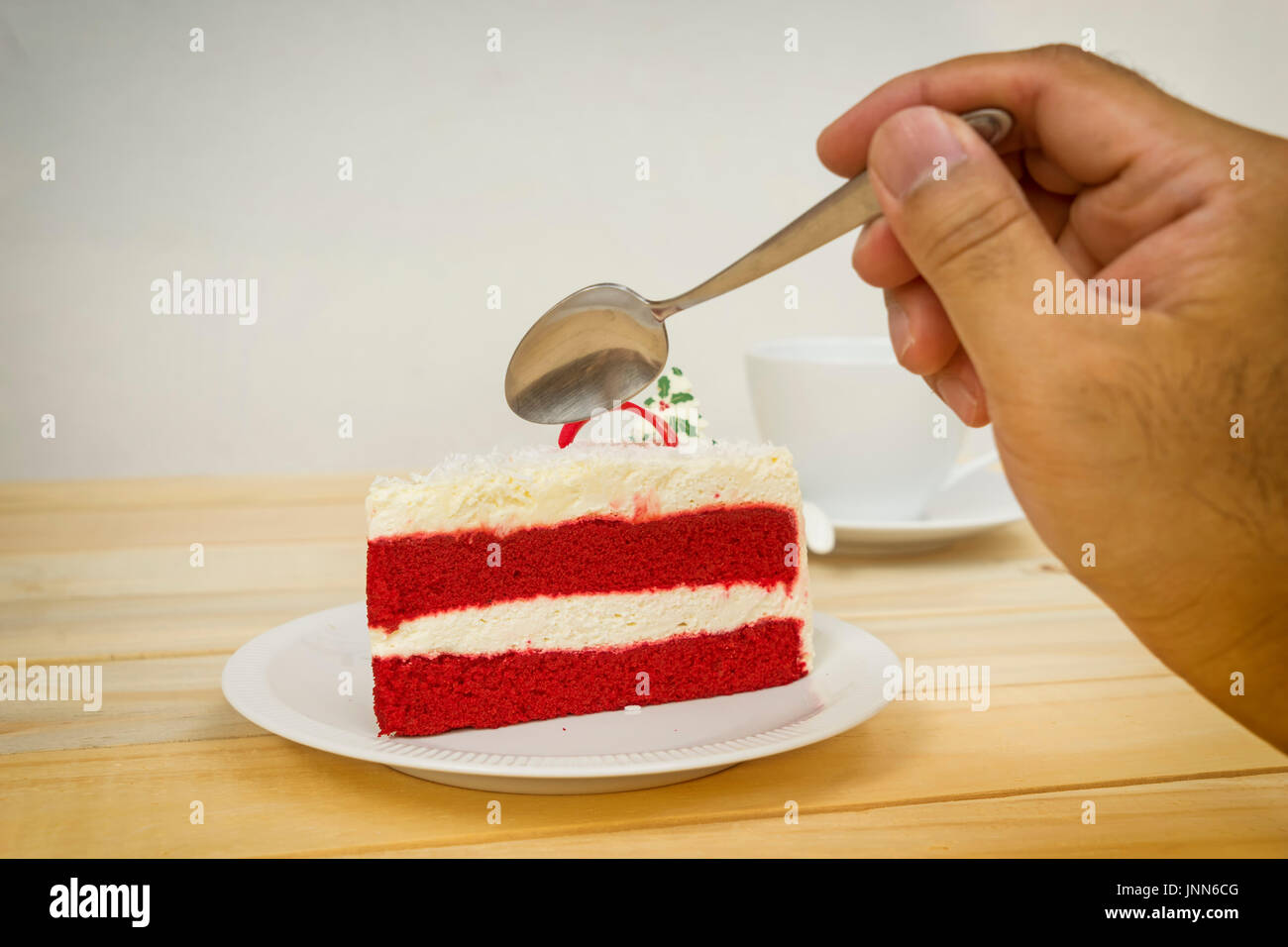 scene-of-red-velvet-cake-and-spoon-on-hand-and-wood-table-can-use-JNN6CG.jpg