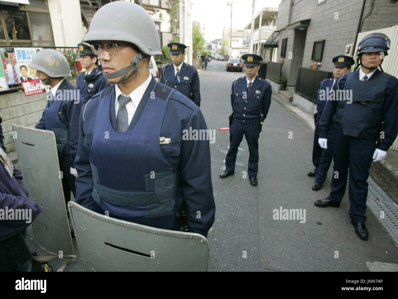 TOKYO, Japan - Police officers seal off a road that leads to an apartment in Machida, Tokyo where a man armed with a handgun barricaded himself on April 20. He had allegedly shot a gangster to death before fleeing into the apartment and fired nine shots out into the open from the apartment. One of the shots hit a police car, but otherwise no one was hurt and no hostages appear to have been taken, the police said. (Kyodo) Stock Photo
