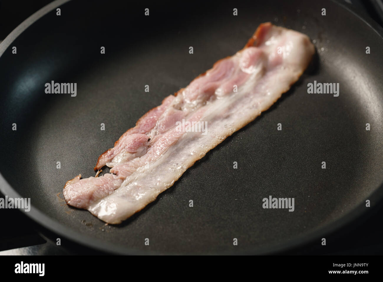 Bacon cooking in a frying pan Stock Photo - Alamy