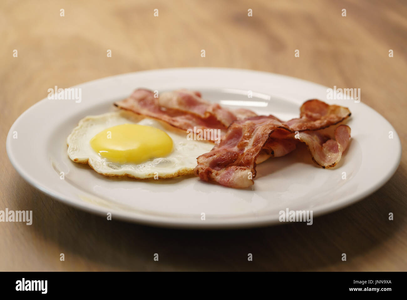 fried egg with crispy bacon stripes on plate Stock Photo - Alamy