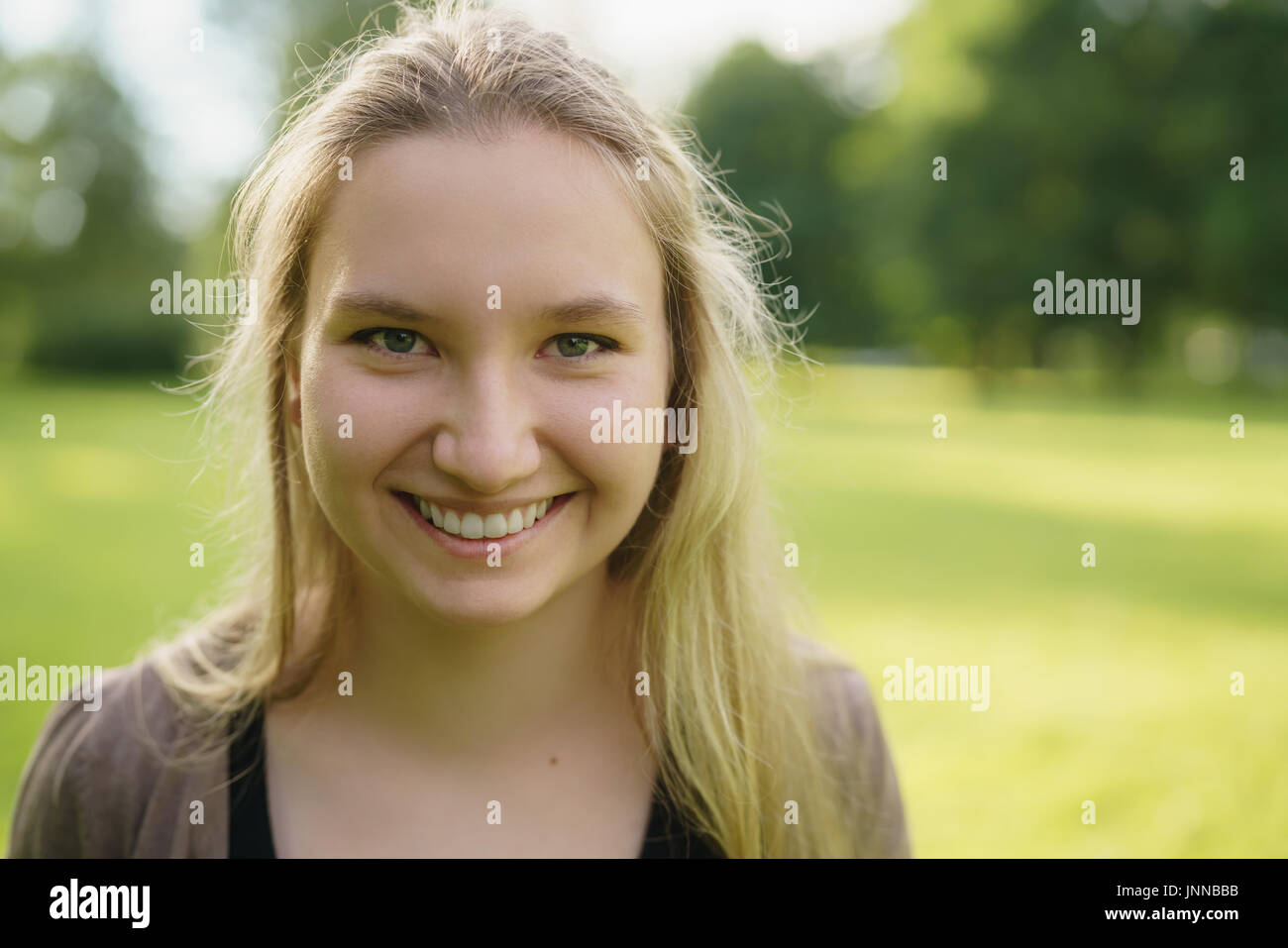 teen girl smiling in green park in sunny summer evening Stock Photo