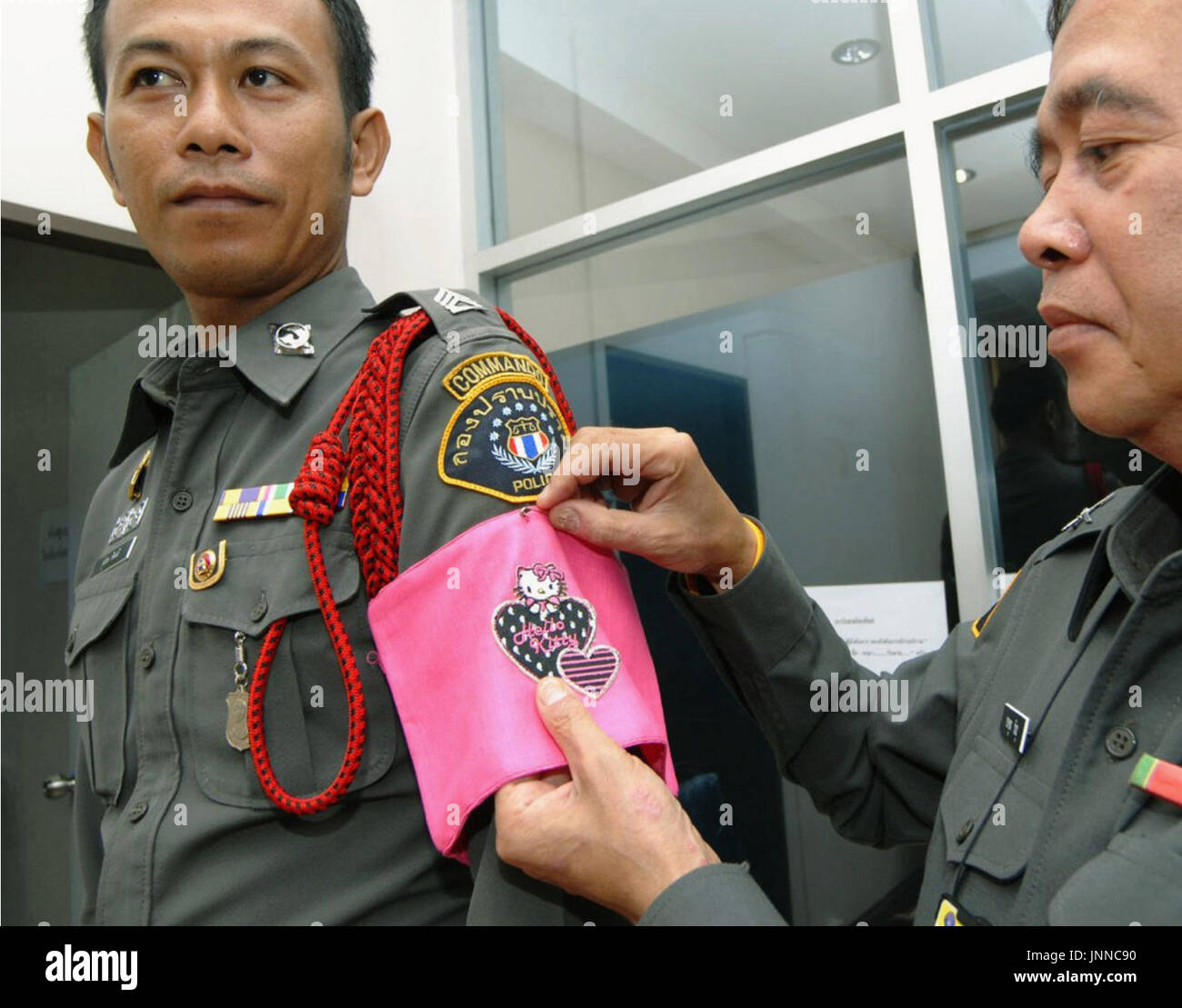 Verrast zijn welzijn hypotheek BANGKOK, Thailand - A police officer pins a pink "Hello Kitty" armband on  another officer's arm on Aug. 7 in Bangkok. Royal Thai Police announce a  new policy in which officers who