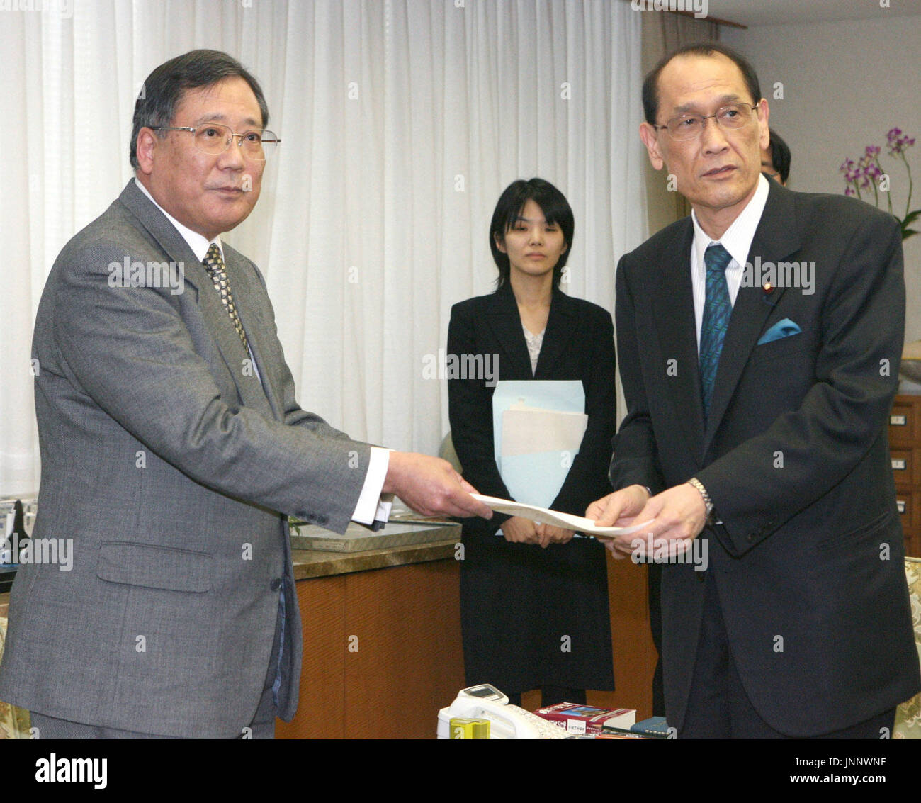 TOKYO, Japan - Takehiko Sugiyama (L), head of the Textbook Authorization Council, hands a report to education minister Kisaburo Tokai (R) on Dec. 26 in which the council approved requests by textbook publishers to reinstate references to the Japanese military's role in forcing civilians to commit mass suicides during the 1945 Battle of Okinawa. (Kyodo) Stock Photo