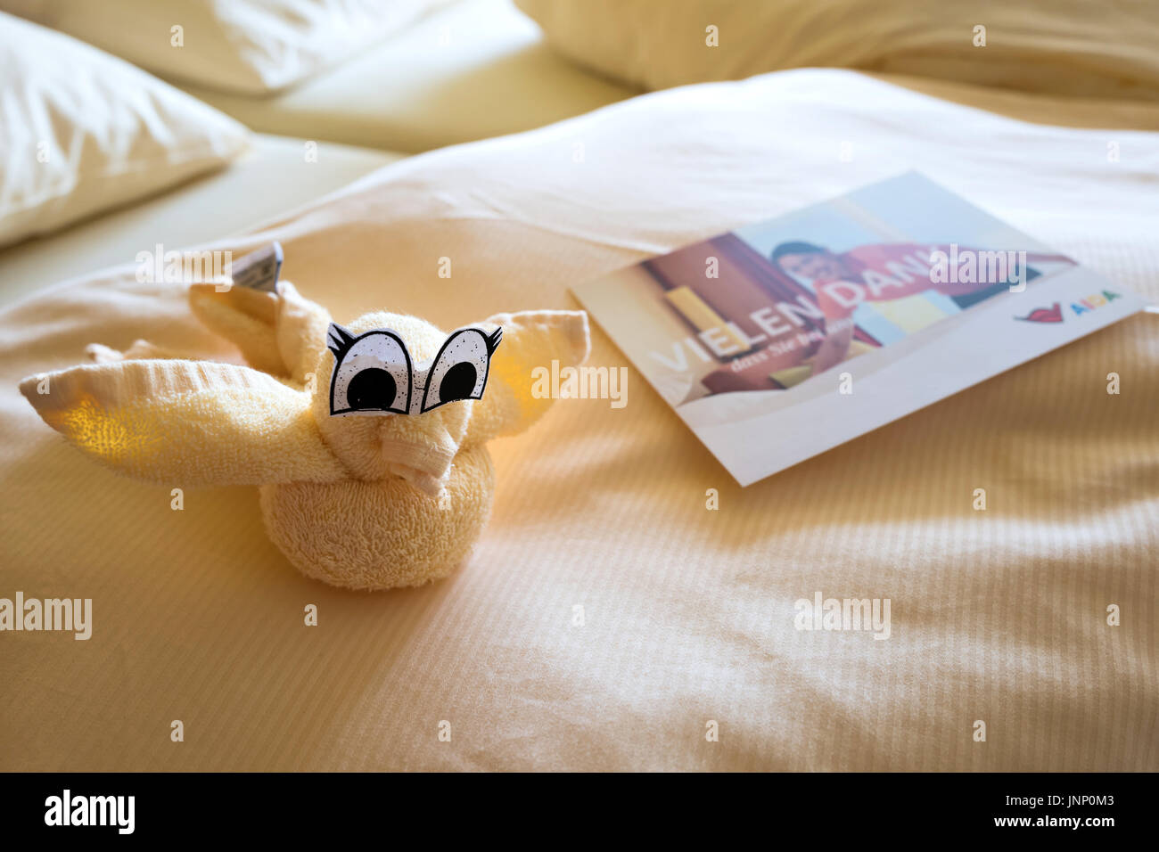 Bird on the bed of a cabin aboard AIDAsol, folded in towl origami by the housekeeping crew. AIDA Cruises is one of ten brands owned by Carnival Corp. Stock Photo