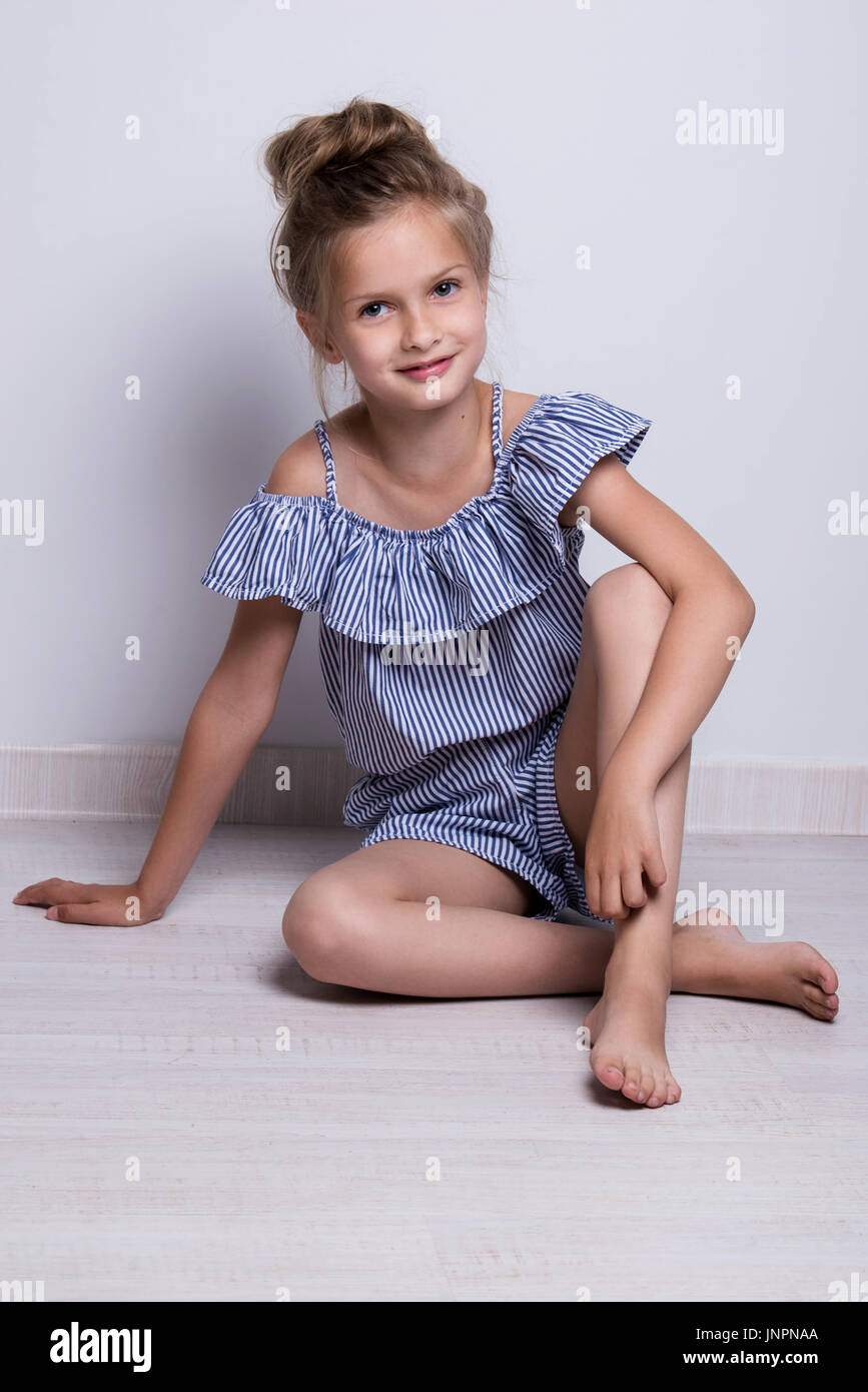 Beautiful little fashion model on white background. Portrait of cute smiling girl posing in studio Stock Photo