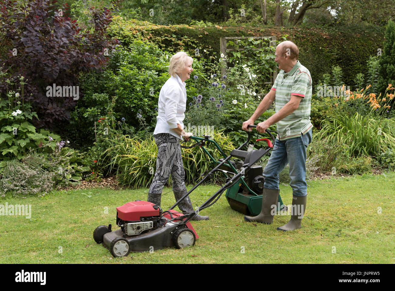 Man and woman with lawn mowers working in a country garden Stock Photo