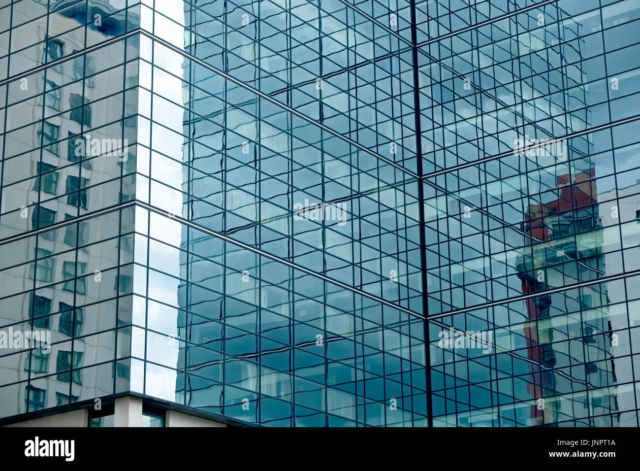 A modern glass commercial building with reflections of other commercial buidlings Stock Photo