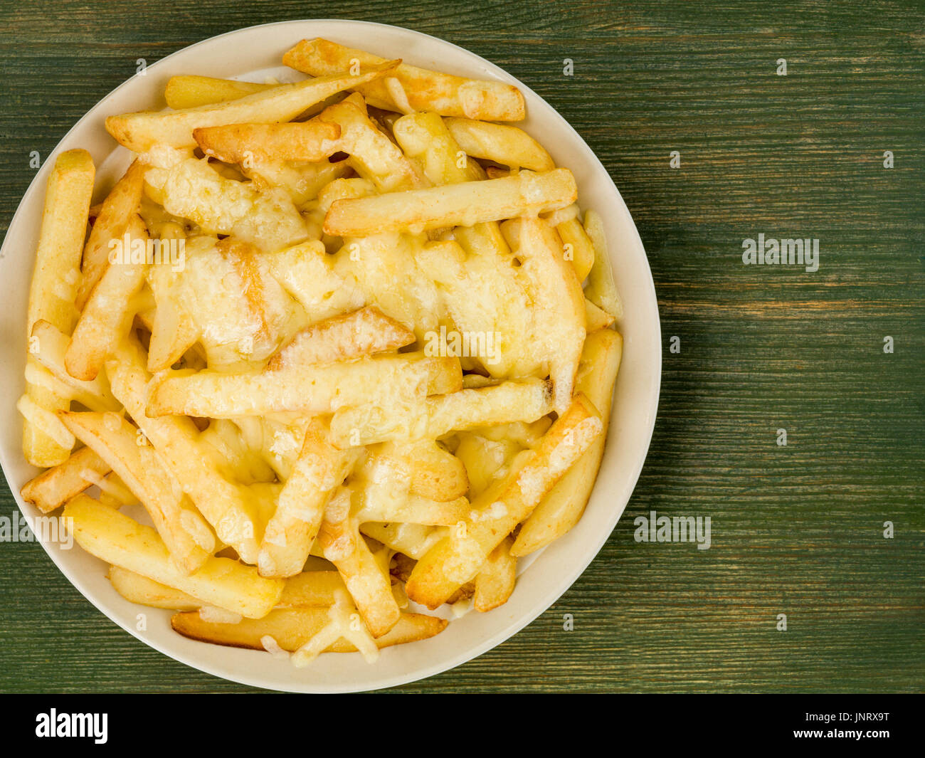 Bowl of Fried and Grilled Cheesy Chips Against a Green Wooden