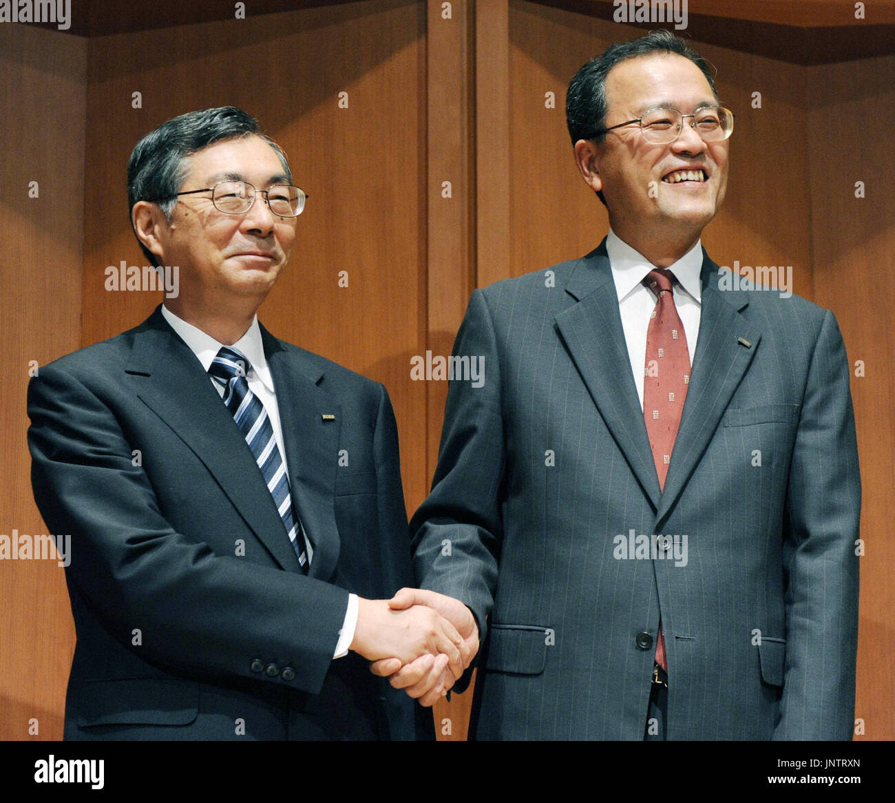 TOKYO, Japan - KDDI Corp. President and Chairman Tadashi Onodera (L) and Senior Vice President Takashi Tanaka shake hands during a news conference in Tokyo on Sept. 10, 2010, after the telecommunications firm announced Tanaka's promotion to president, replacing Onodera on Dec. 1. (Kyodo) Stock Photo