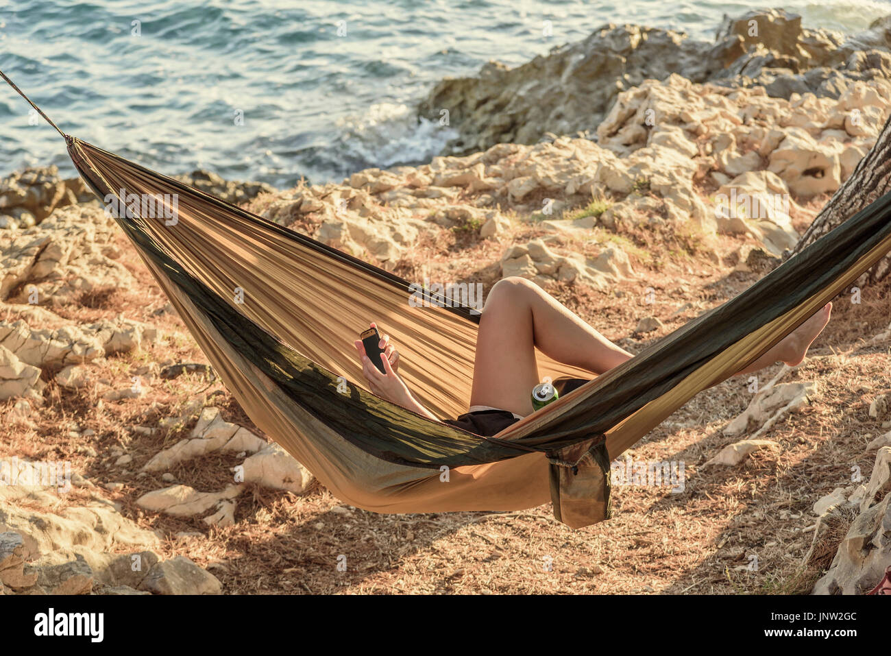 Young woman looking at mobile phone in hammock Stock Photo