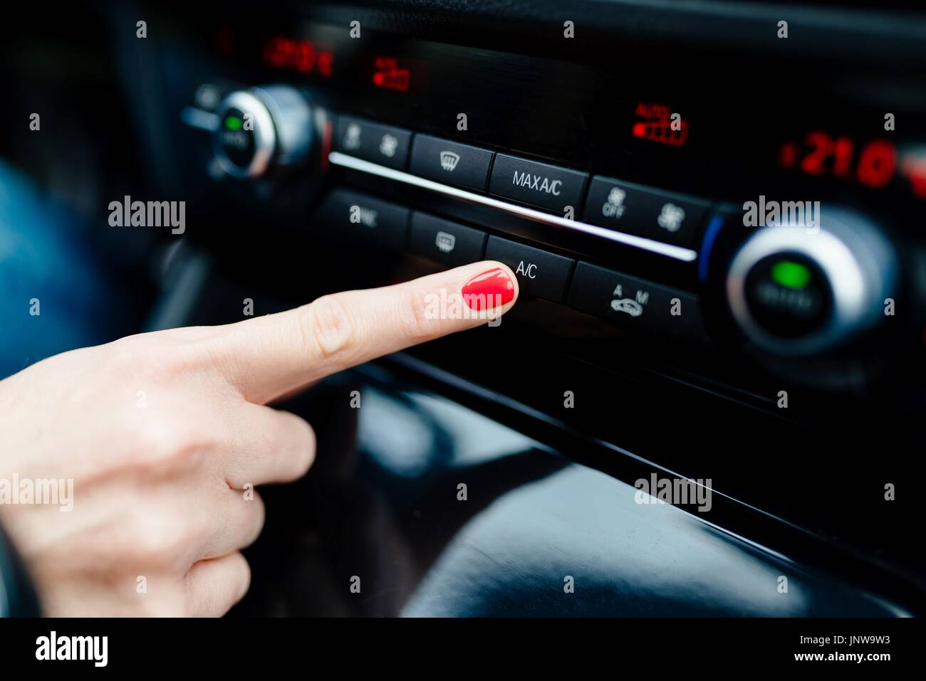 Woman turns on air conditioning in the car. Modern car interior Stock Photo