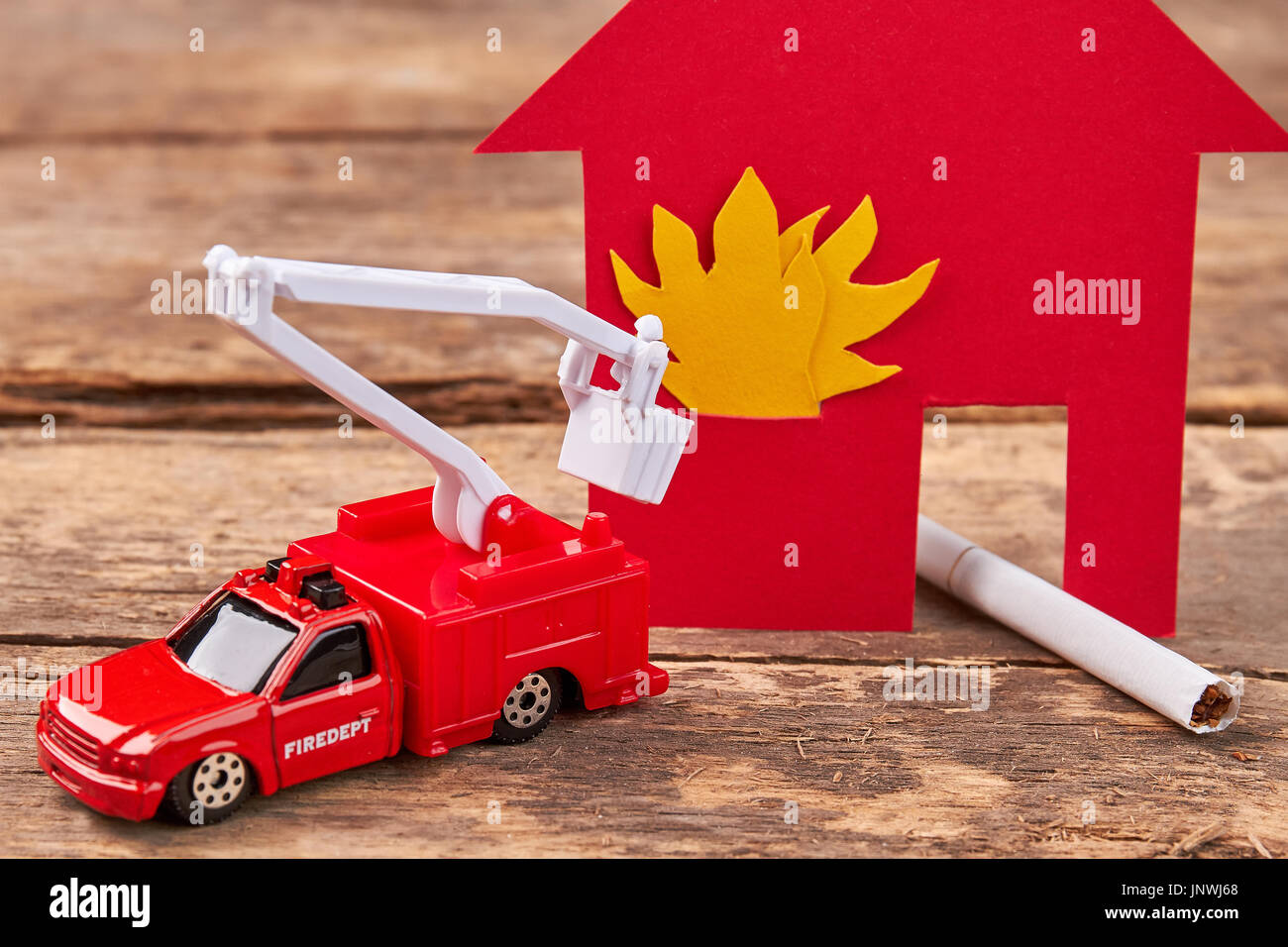 Toy fire engine extinguishes flaming house. Stock Photo