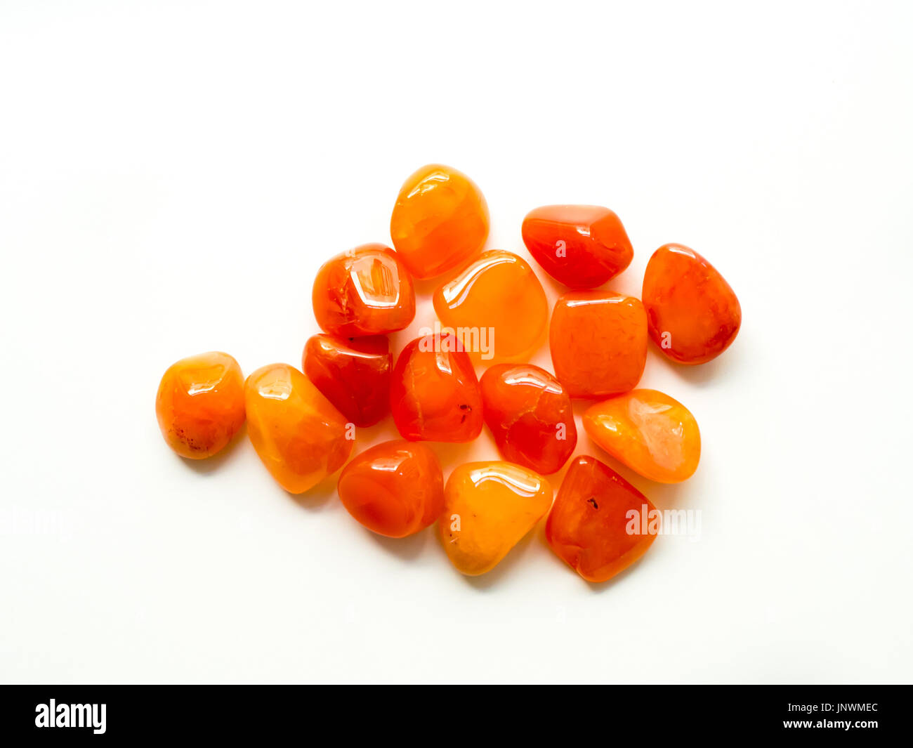Tumbled carnelian stones on white background for crystal therapy treatments and reiki Stock Photo