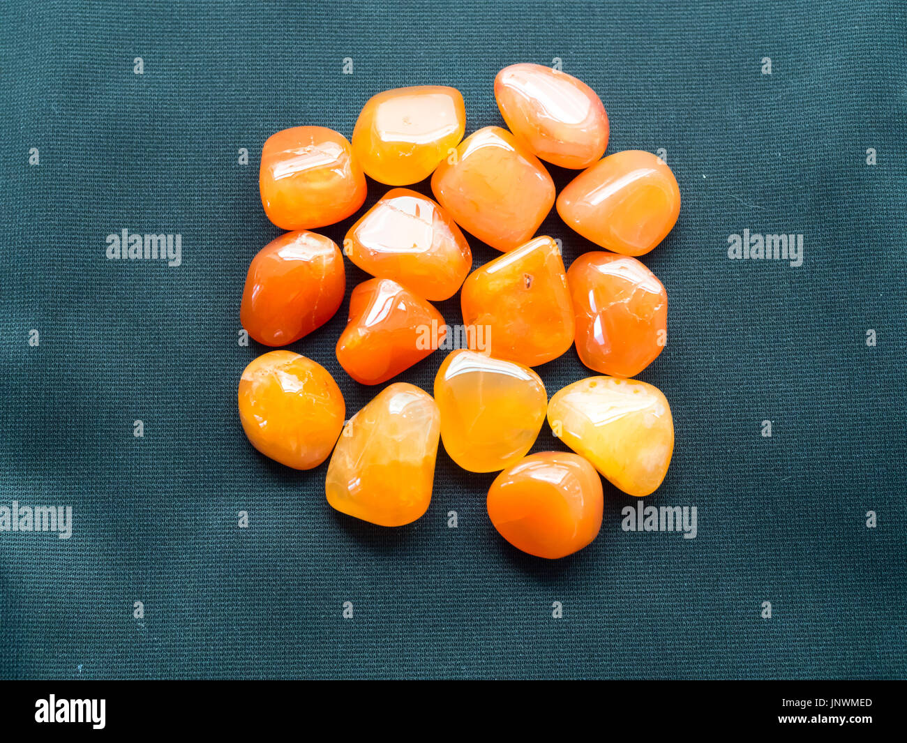 Tumbled carnelian stones on black cloth for crystal therapy treatments and reiki Stock Photo