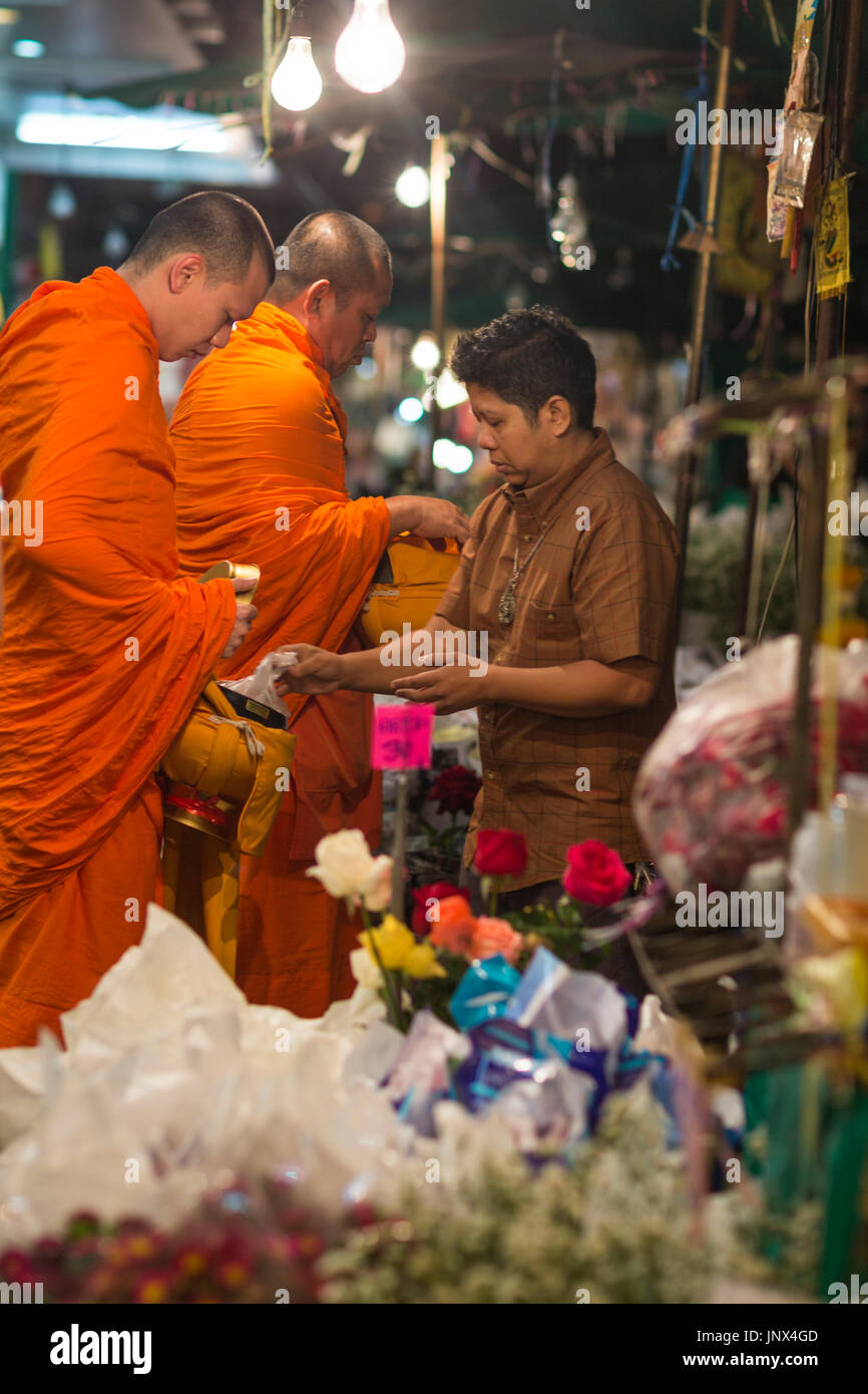 Bangkok, Thailand - February 18, 2015: Monks receiving alms at the Pak Khlong Talat flower market in Yaowarat and Pahurat in Bangkok at night Stock Photo