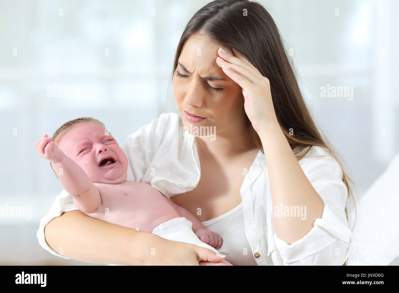Desperate mother holding her angry baby crying Stock Photo